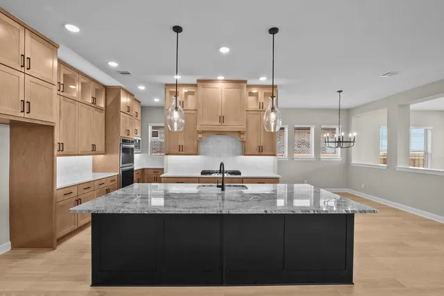 a kitchen with kitchen island granite countertop a sink a counter top space and stainless steel appliances