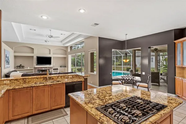 a kitchen with stainless steel appliances granite countertop a stove top oven a sink dishwasher and a refrigerator with wooden cabinets