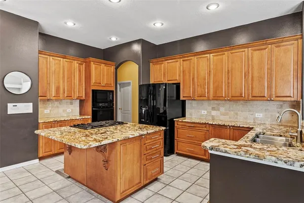 a kitchen with stainless steel appliances kitchen island granite countertop a stove a sink and a refrigerator