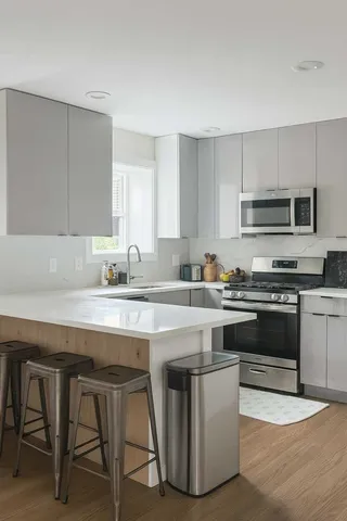 a kitchen with stainless steel appliances a stove a sink a microwave a refrigerator and cabinets