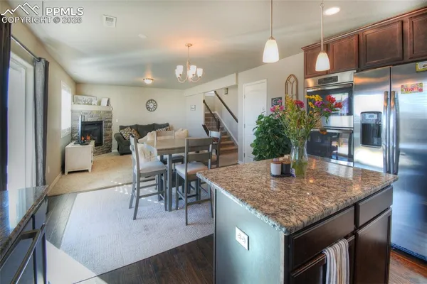 a kitchen with granite countertop kitchen island stainless steel appliances a dining table and chairs
