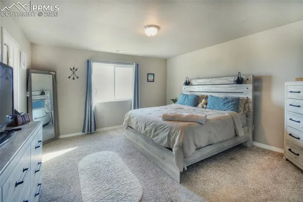 a bedroom with a bed and a flat tv screen on dresser