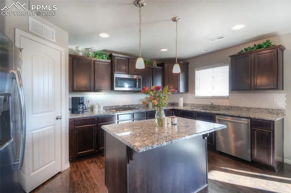 a kitchen with stainless steel appliances granite countertop a sink a stove and refrigerator