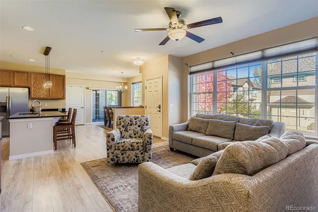 a living room with furniture kitchen view and a large window