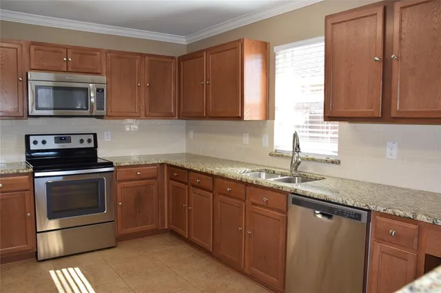 a kitchen with granite countertop a sink stove and microwave