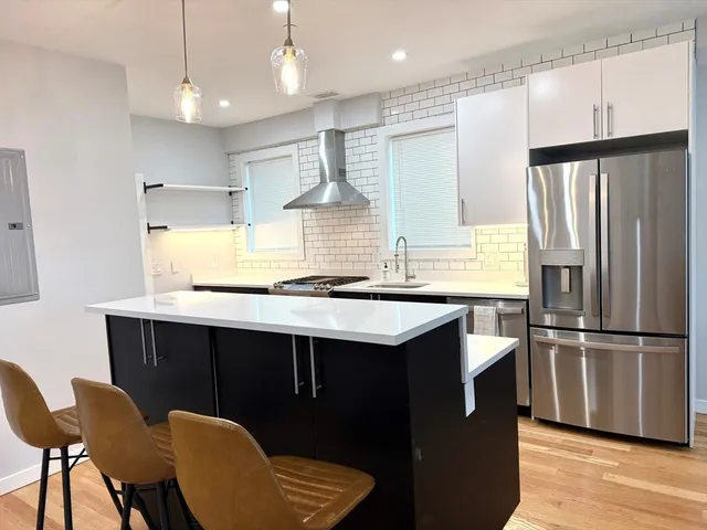 a kitchen with kitchen island stainless steel appliances a sink and a refrigerator
