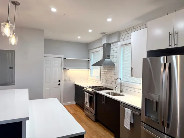 a large kitchen with stainless steel appliances a sink a stove a refrigerator and a cabinets