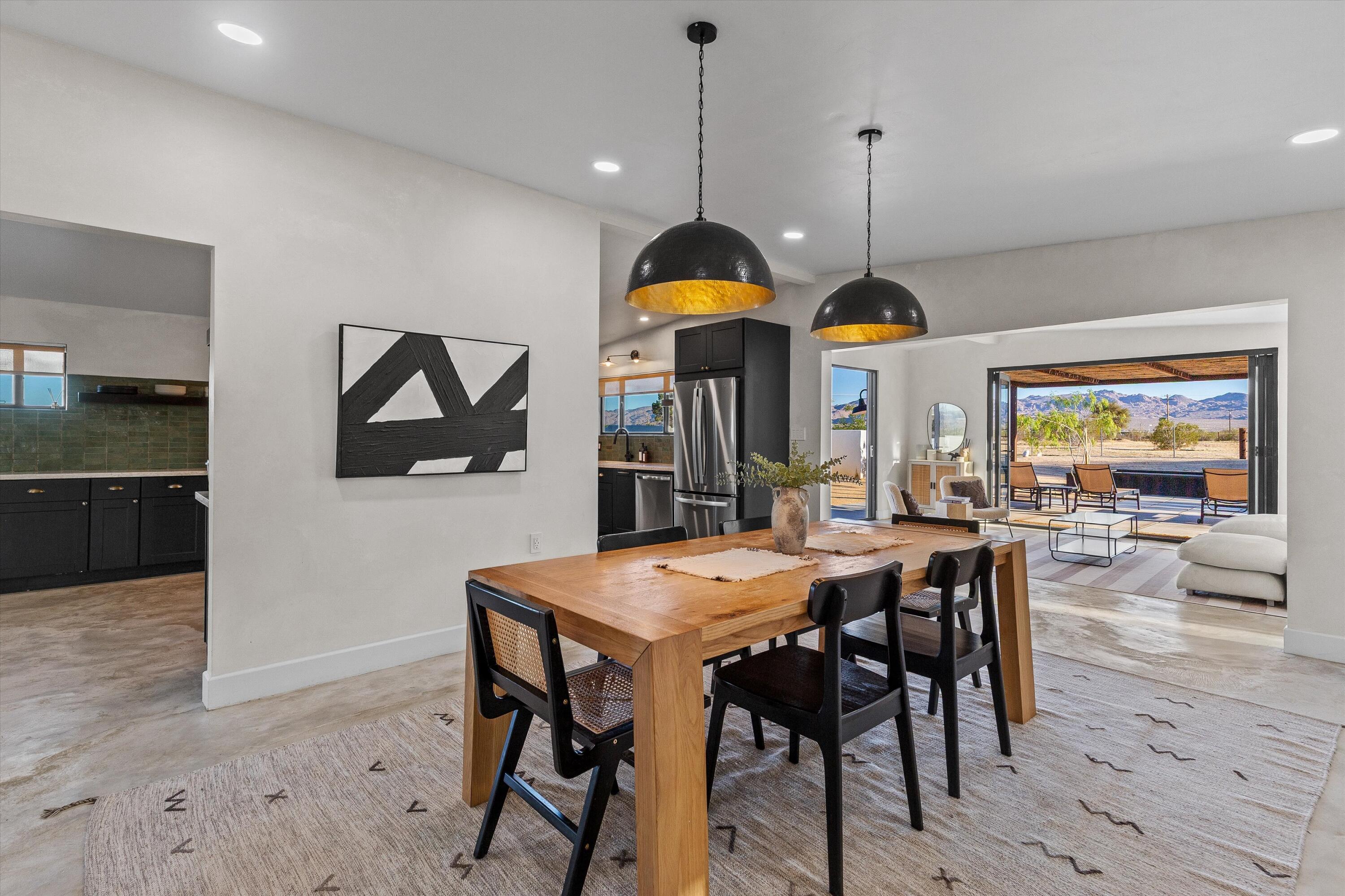 4610 Sunkist Road Joshua Tree, CA 92252 - Photo 24 of 55 a view of a dining room and livingroom with furniture wooden floor a rug a painting and a chandelier