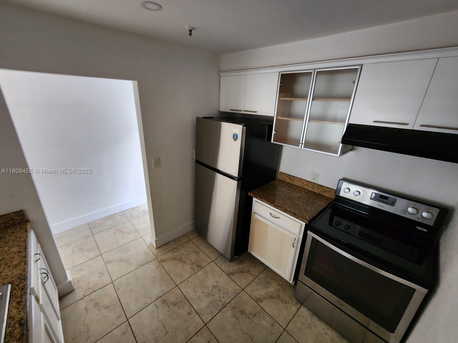 677 Northeast 24th Street, Unit 607 Miami, FL 33137 - Photo 10 of 29 a view of a refrigerator in kitchen and an empty room with wooden floor
