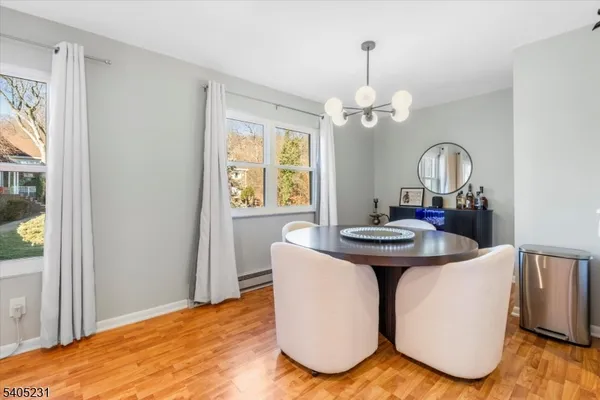 a dining room with wooden floor a chandelier a wooden table and chairs