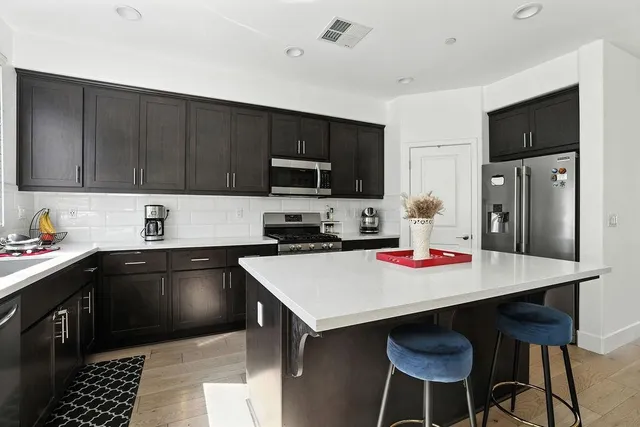 a kitchen with stainless steel appliances a sink dishwasher a stove a microwave and wooden cabinets