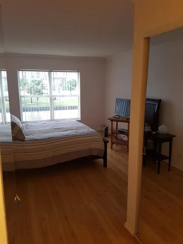 a bedroom with a bed wooden floor and a large window