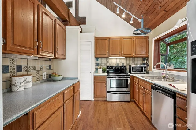 a kitchen with stainless steel appliances granite countertop a sink a stove and cabinets