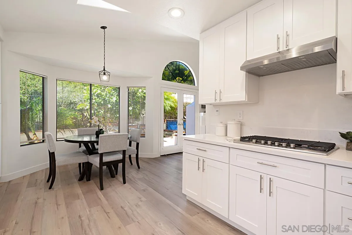 4256 Caminito Terviso San Diego, CA 92122 - Photo 16 of 32 a kitchen with stainless steel appliances granite countertop a stove a sink dishwasher and white cabinets with wooden floor