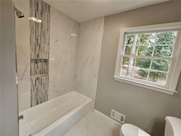 a bathroom with a tub shower and toilet