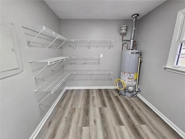 a walk in closet with wooden floor