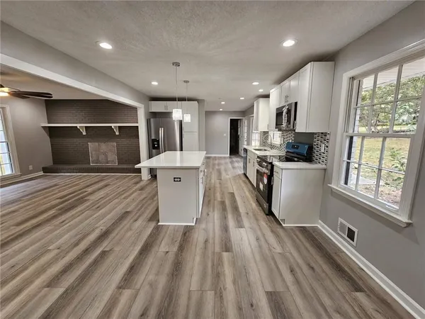 a large kitchen with kitchen island a large window appliances and cabinets