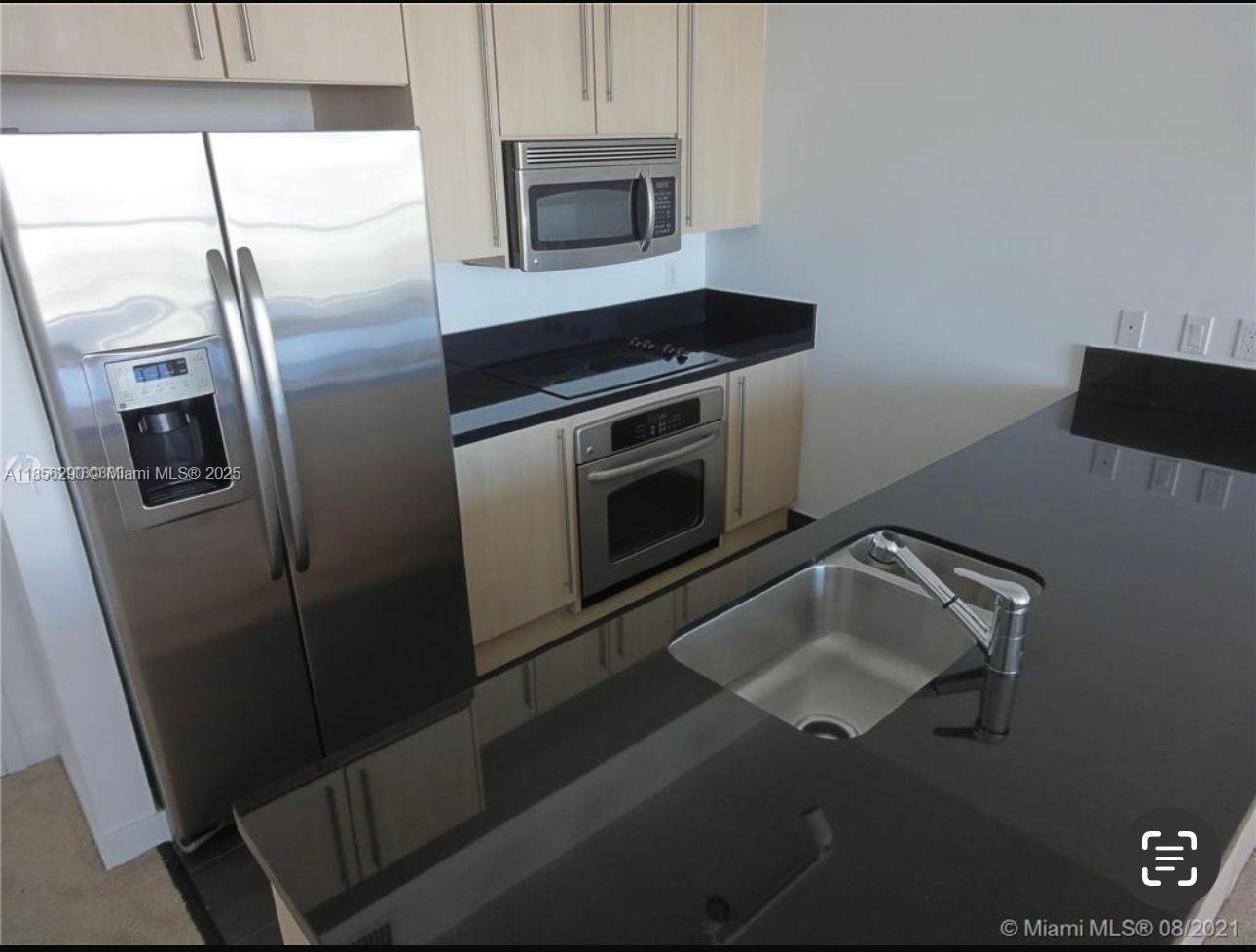 1111 Southwest 1st Avenue, Unit 3122N Miami, FL 33130 - Photo 3 of 9 a kitchen with stainless steel appliances granite countertop a refrigerator a stove and a sink with wooden floor