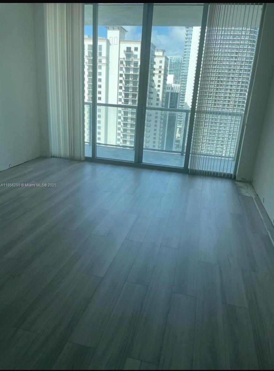 1111 Southwest 1st Avenue, Unit 3122N Miami, FL 33130 - Photo 6 of 9 a view of an empty room with wooden floor and a window