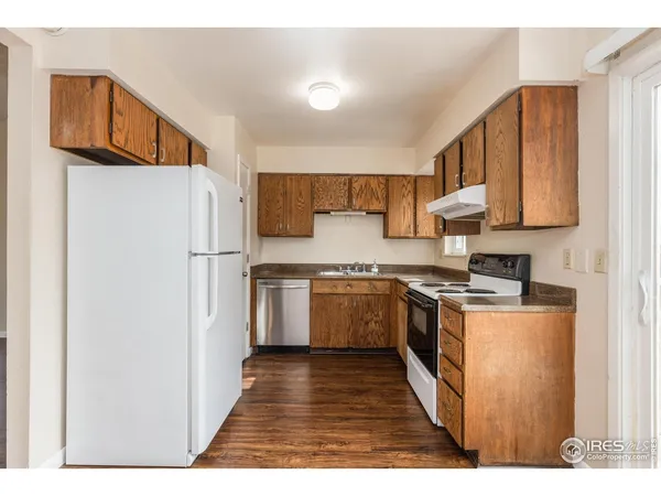 a kitchen with a refrigerator a stove top oven a sink and dishwasher with wooden floor