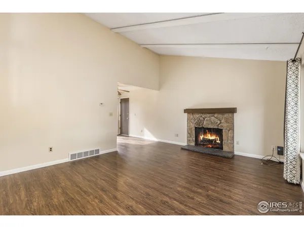 a view of an empty room with wooden floor fireplace and a window