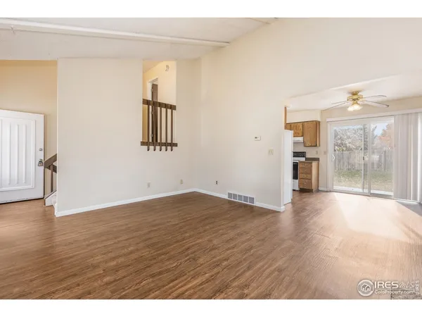 a view of an empty room with window and wooden floor