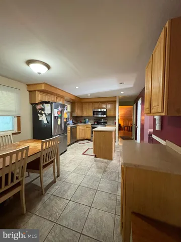 a living room with a table chairs and a refrigerator