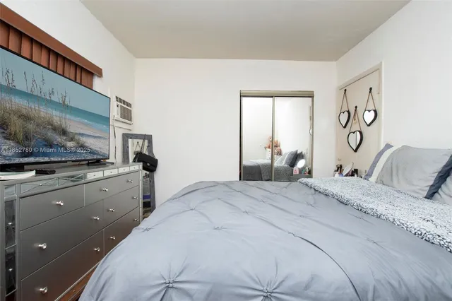 a bedroom with a large bed and a flat tv screen on dresser