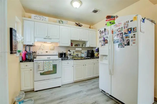 a kitchen with refrigerator and white cabinets