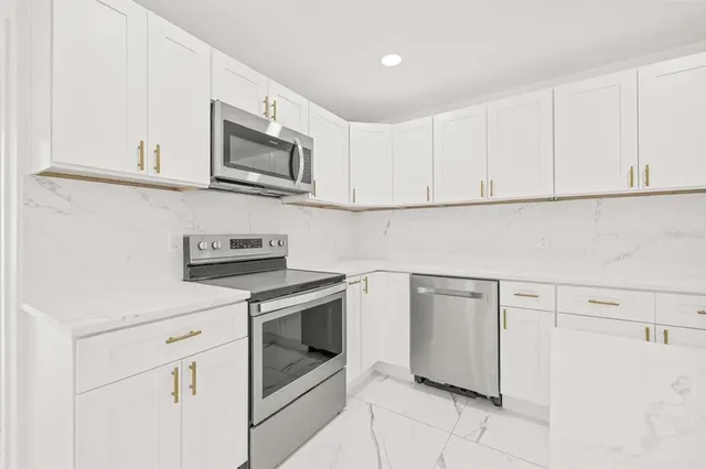 a kitchen with white cabinets stainless steel appliances and sink