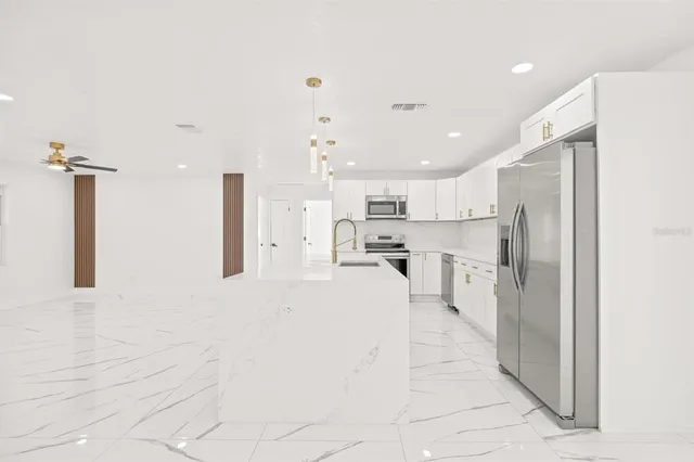 a kitchen with stainless steel appliances kitchen island sink refrigerator and microwave