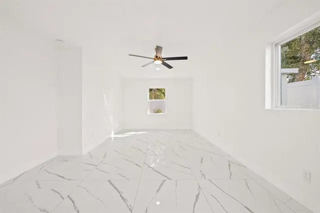 an empty room with windows and ceiling fan
