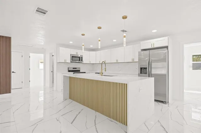 a kitchen with kitchen island a sink stainless steel appliances and cabinets