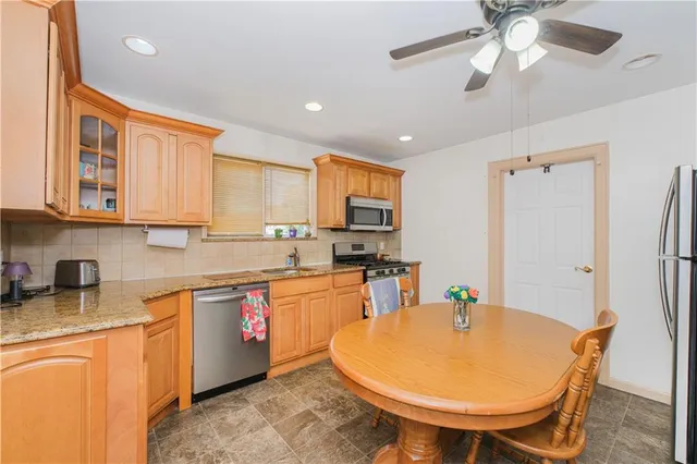 a kitchen with stainless steel appliances granite countertop a sink a stove a refrigerator cabinets and dining table