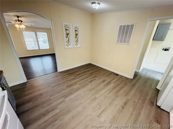a view of an empty room with wooden floor and a window
