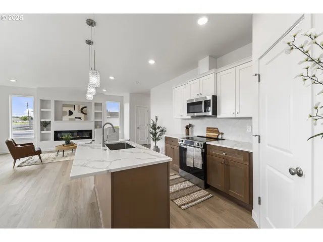 a kitchen with stainless steel appliances kitchen island granite countertop a stove top oven a sink a counter top space and cabinets