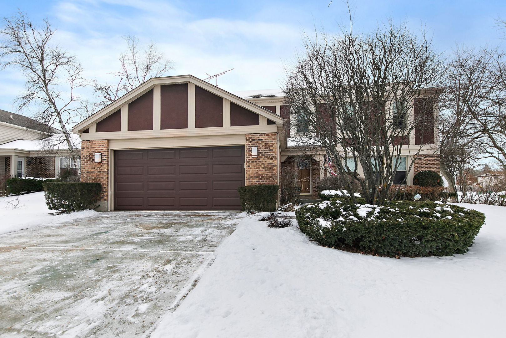 a front view of a house with a yard covered in snow