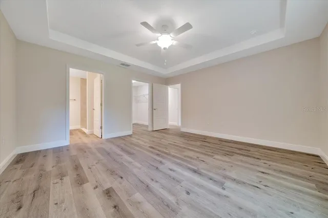 an empty room with wooden floor and ceiling fan