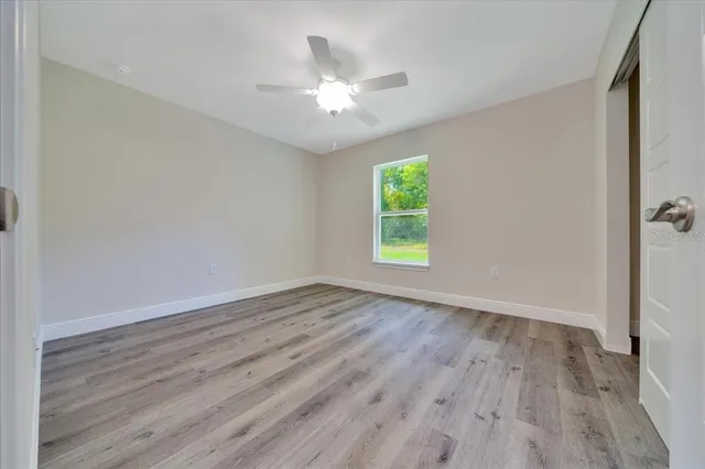 an empty room with wooden floor chandelier and windows