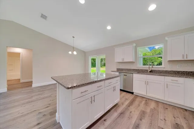a kitchen with granite countertop white cabinets white appliances a sink and a window