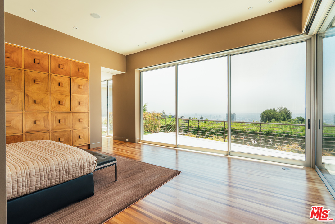 1470 Carla Ridge Beverly Hills, CA 90210 - Photo 13 of 44 a bedroom with a large window and a wooden floor
