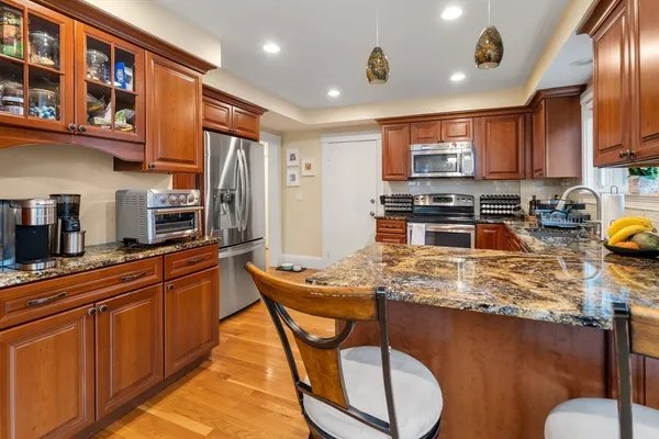 a kitchen with stainless steel appliances granite countertop a stove top oven a sink dishwasher and cabinets with wooden floor