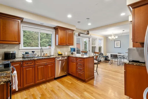 a large kitchen with kitchen island granite countertop a large window and white cabinets