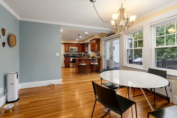 a dining room with wooden floor a chandelier a wooden table and chairs