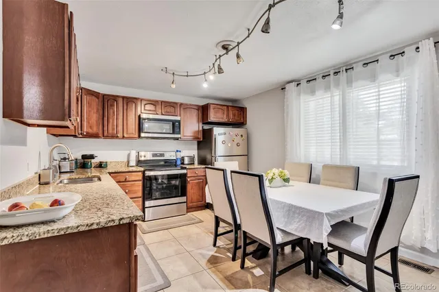 a kitchen with stainless steel appliances granite countertop a stove top oven a sink dishwasher a dining table and chairs with wooden floor