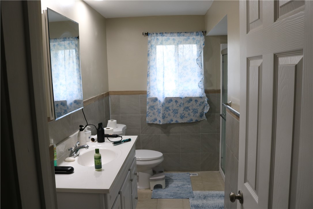3185 Stop 8 Road Dayton, OH 45414 - Photo 9 of 10 This bright bathroom features a vanity, toilet, and a tiled shower.