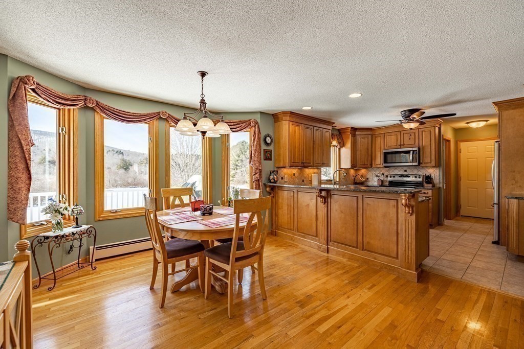 158 Scantic Road Hampden, MA 01036 - Photo 9 of 42 a kitchen with stainless steel appliances granite countertop a stove top oven a sink dishwasher a dining table and chairs with wooden floor