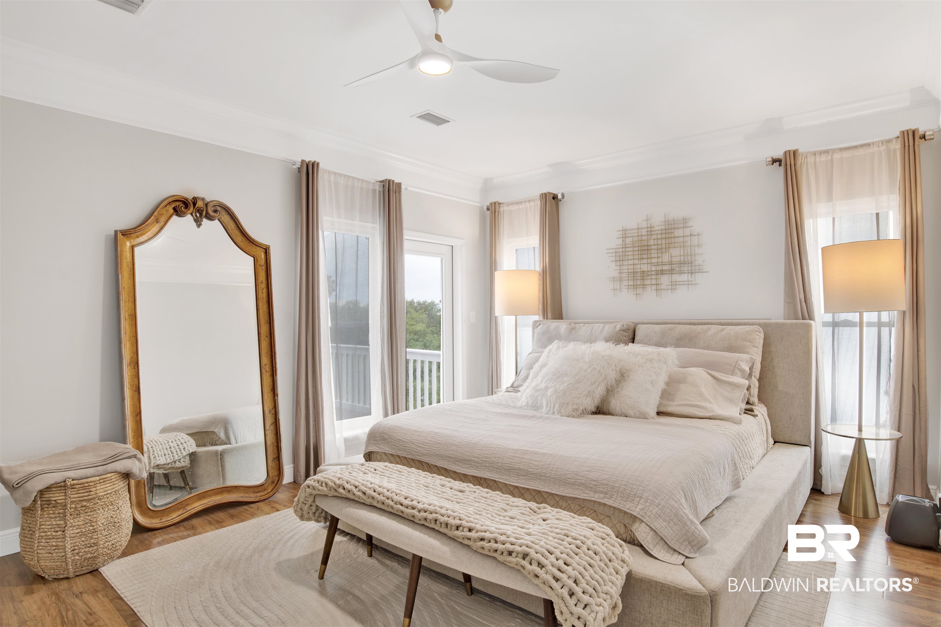 30351 River Road Orange Beach, AL 36561 - Photo 17 of 44 Spacious room featuring wood-finish flooring, a contemporary ceiling fan, crown molding, and two sets of double doors opening to a white railing balcony