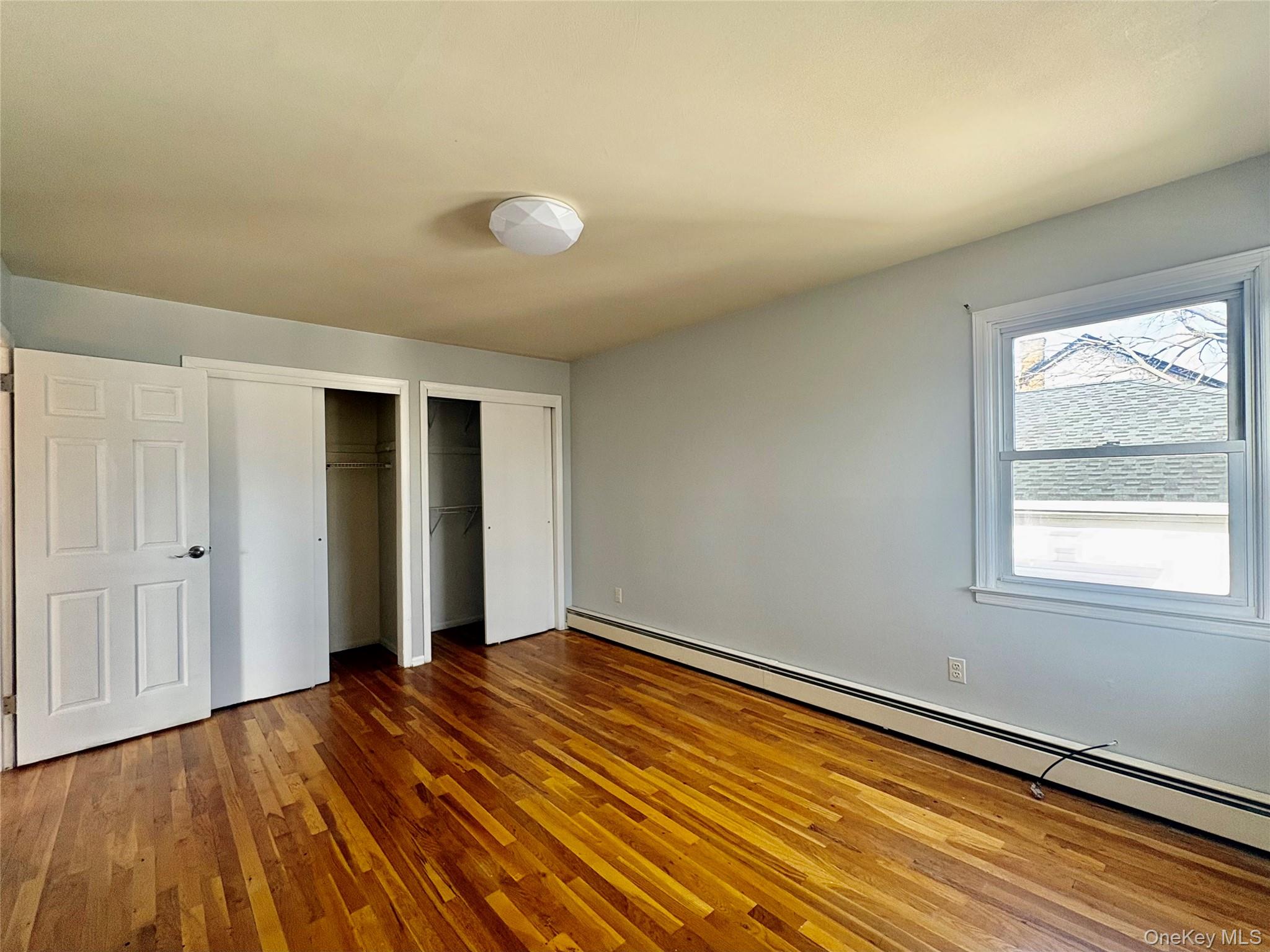 Undisclosed Address Valley Stream, NY 11581 - Photo 7 of 11 an empty room with wooden floor and windows