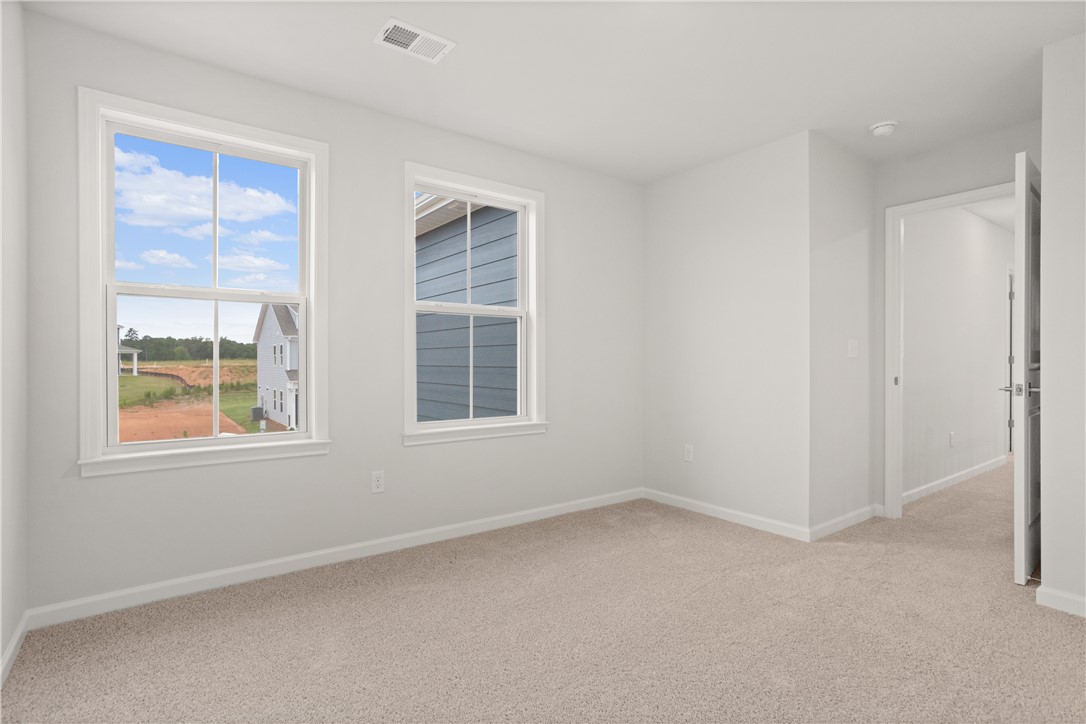 631 Sweetspire Trail, Unit 148 Seneca, SC 29678 - Photo 23 of 36 Two large windows illuminate this serene bedroom, offering views of the developing neighborhood and sky.